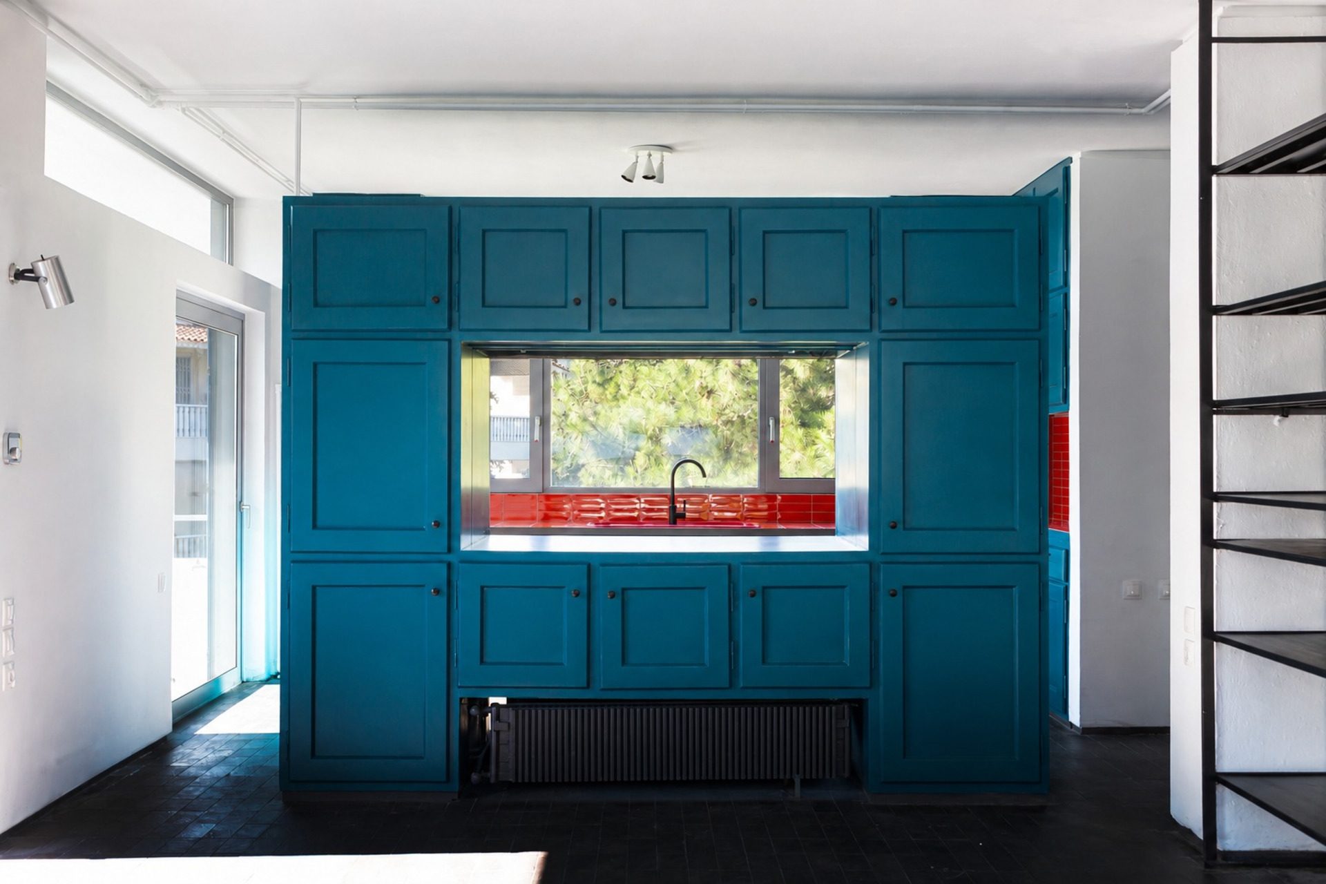 Duplex Residence in Athens with petrol-blue built-in cabinetry around a window