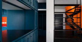 Petrol-blue cabinetry and orange spiral stair in the Duplex Residence in Athens