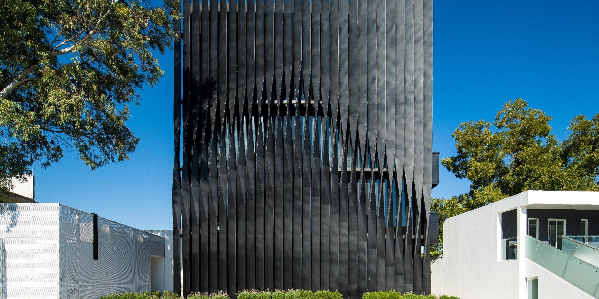 Torre Negra black metal-screened façade behind planted entrance strip