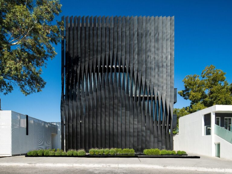 Torre Negra black metal-screened façade behind planted entrance strip