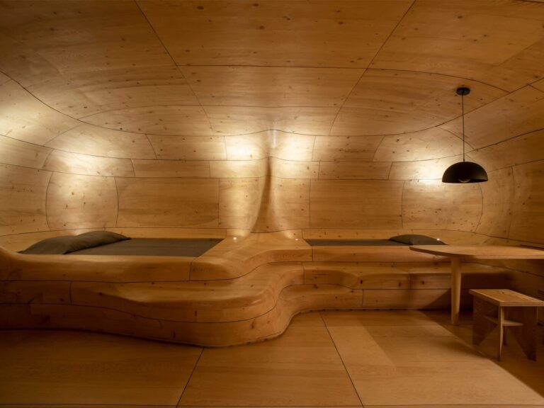 Curved timber structure with integrated sleeping platforms in The Wooden Cave