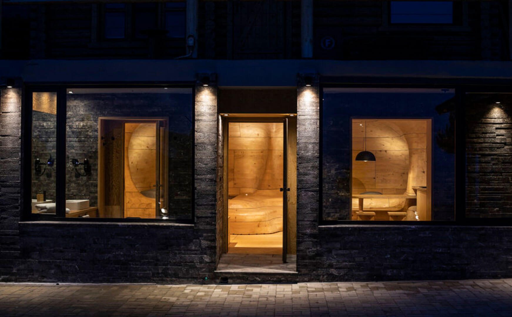 Dark stone exterior with lit timber interior of The Wooden Cave at night