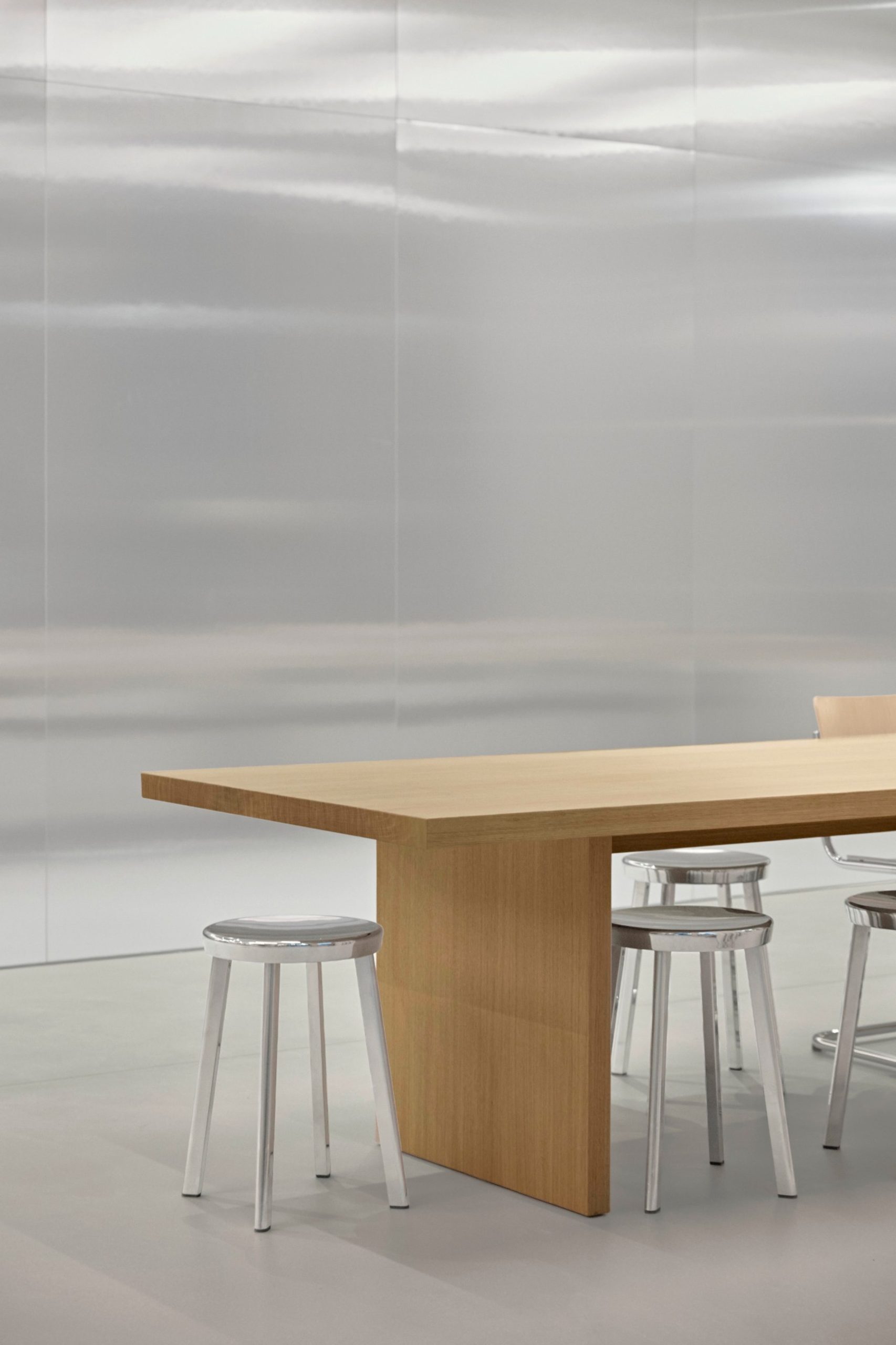 Timber meeting table and stools against mirrored wall at BESTSECRET offices Munich