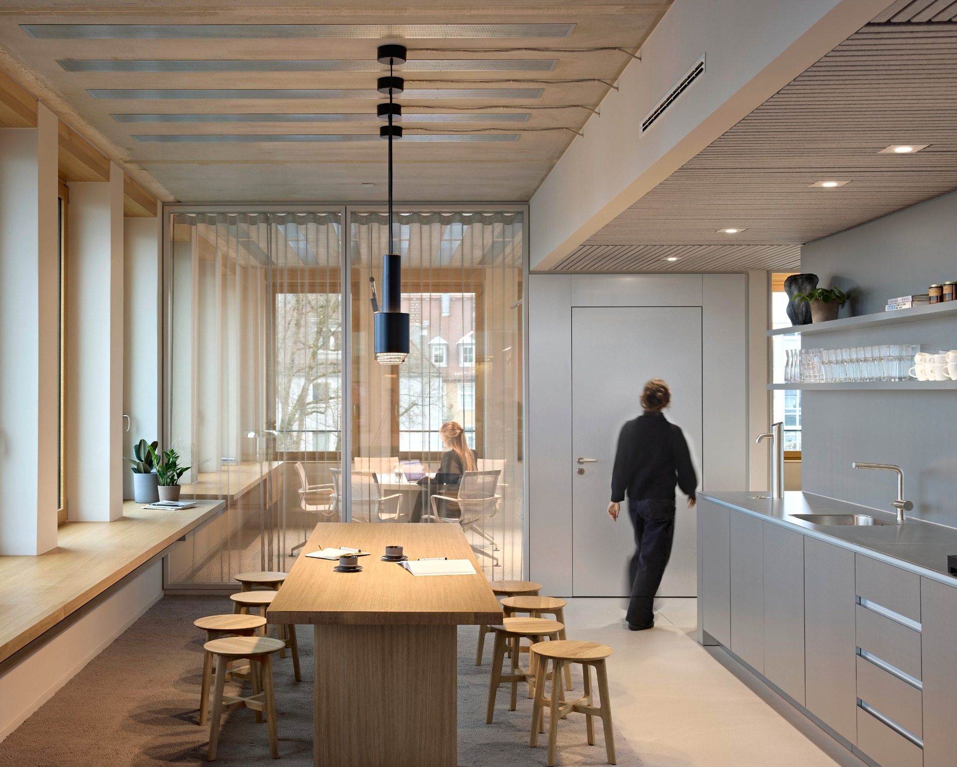 Lounge kitchen with long timber table and stools at BESTSECRET offices Munich