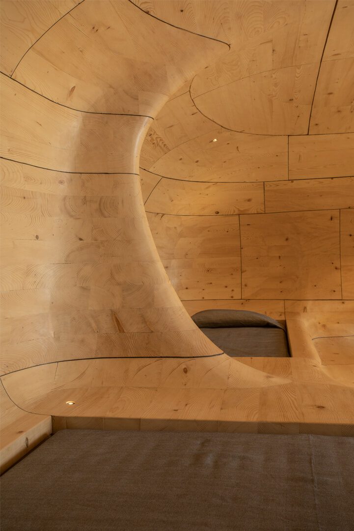 Curved timber wall framing a sleeping niche in The Wooden Cave