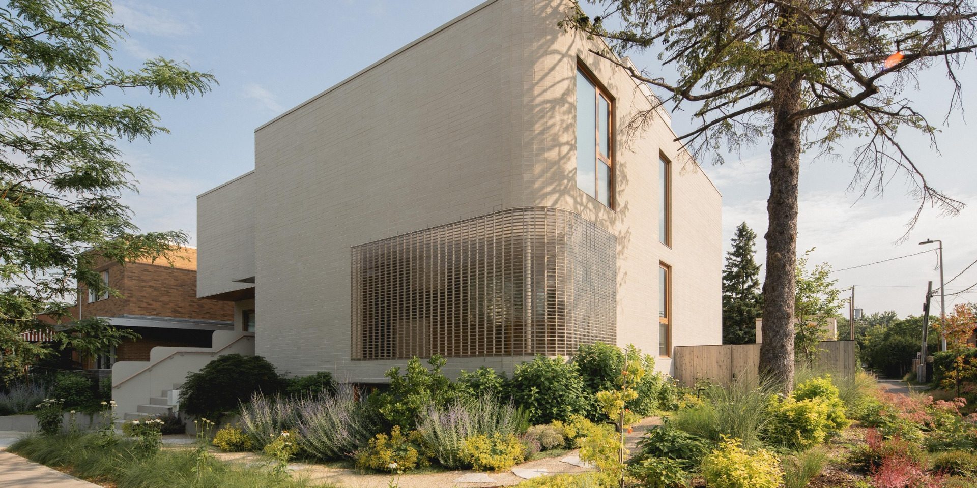 The Lens curved glass-block corner and beige brick volumes in Montreal