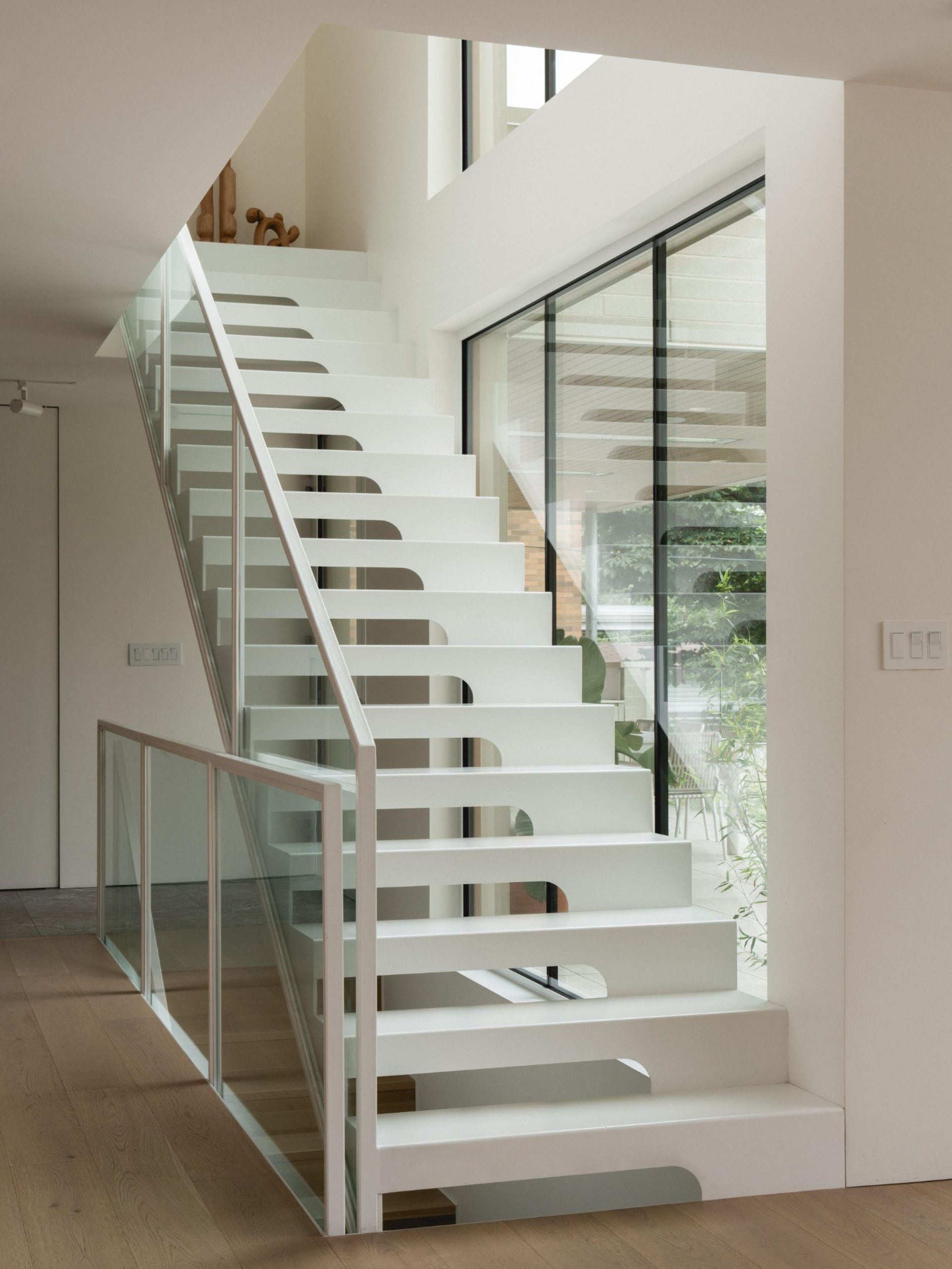 Floating white steel staircase with glass balustrades at The Lens