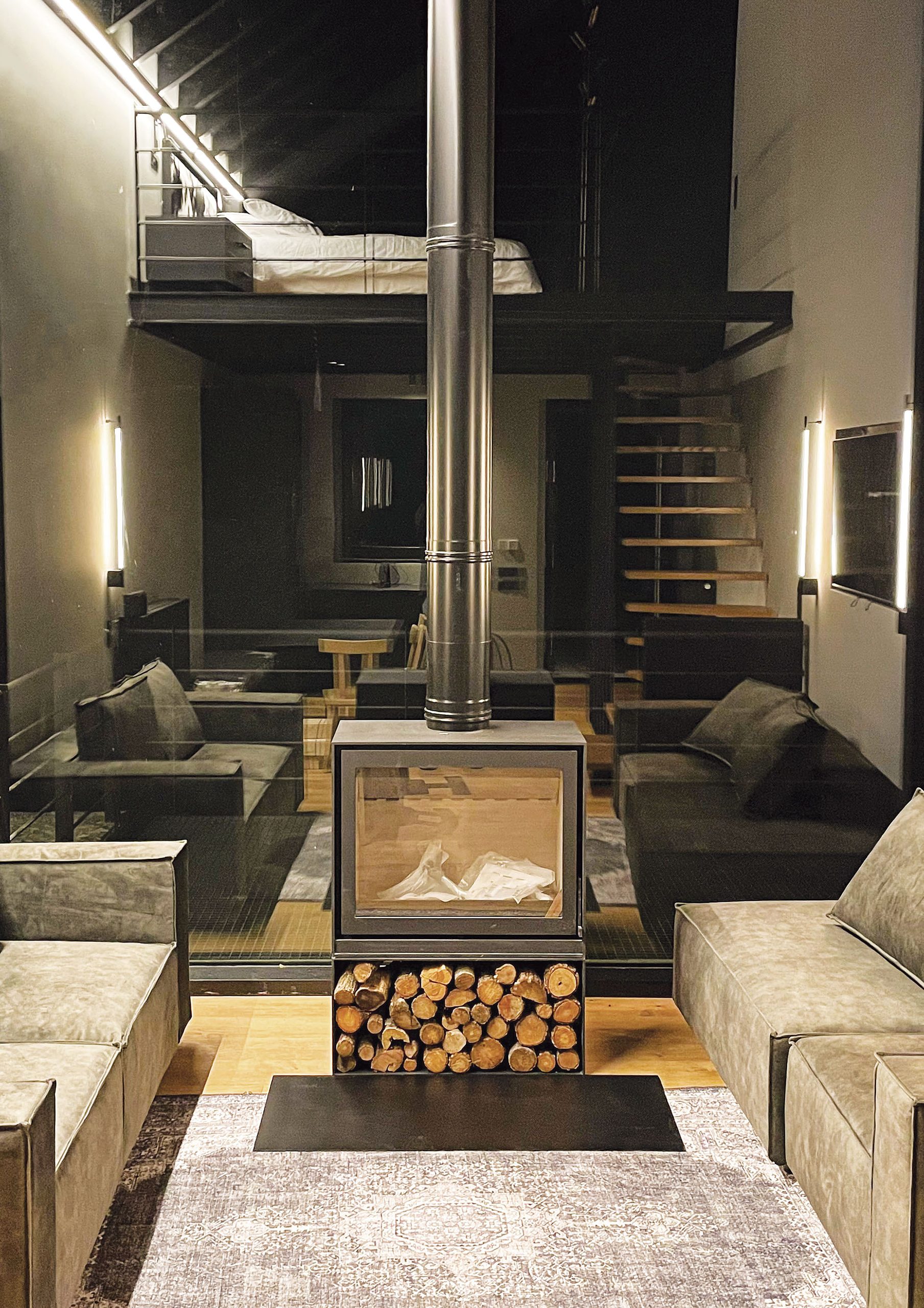 Double-height living room with black metal stove at Hermitage 1310