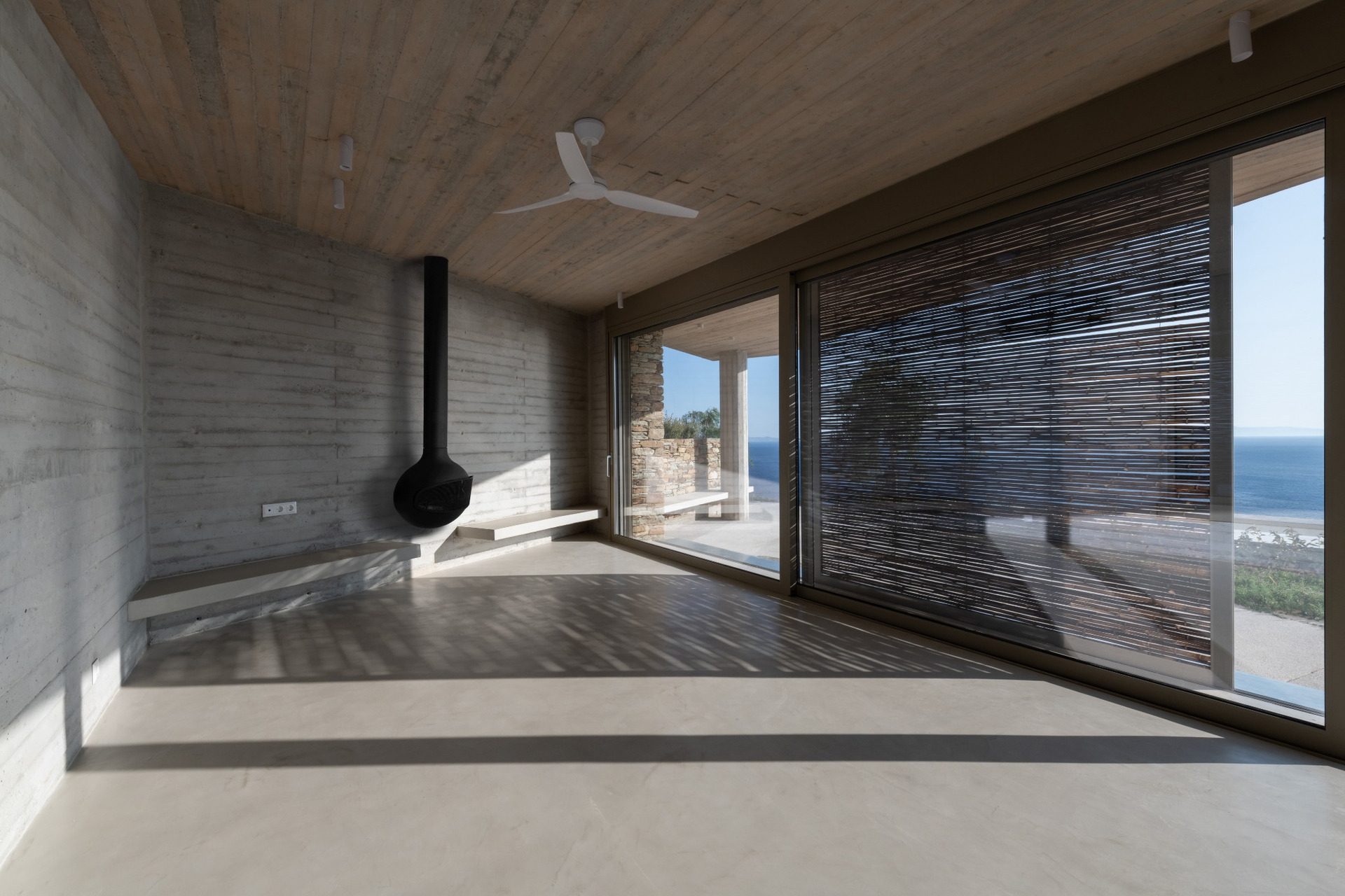 Living room with fireplace and bamboo screens in residence B in Andros