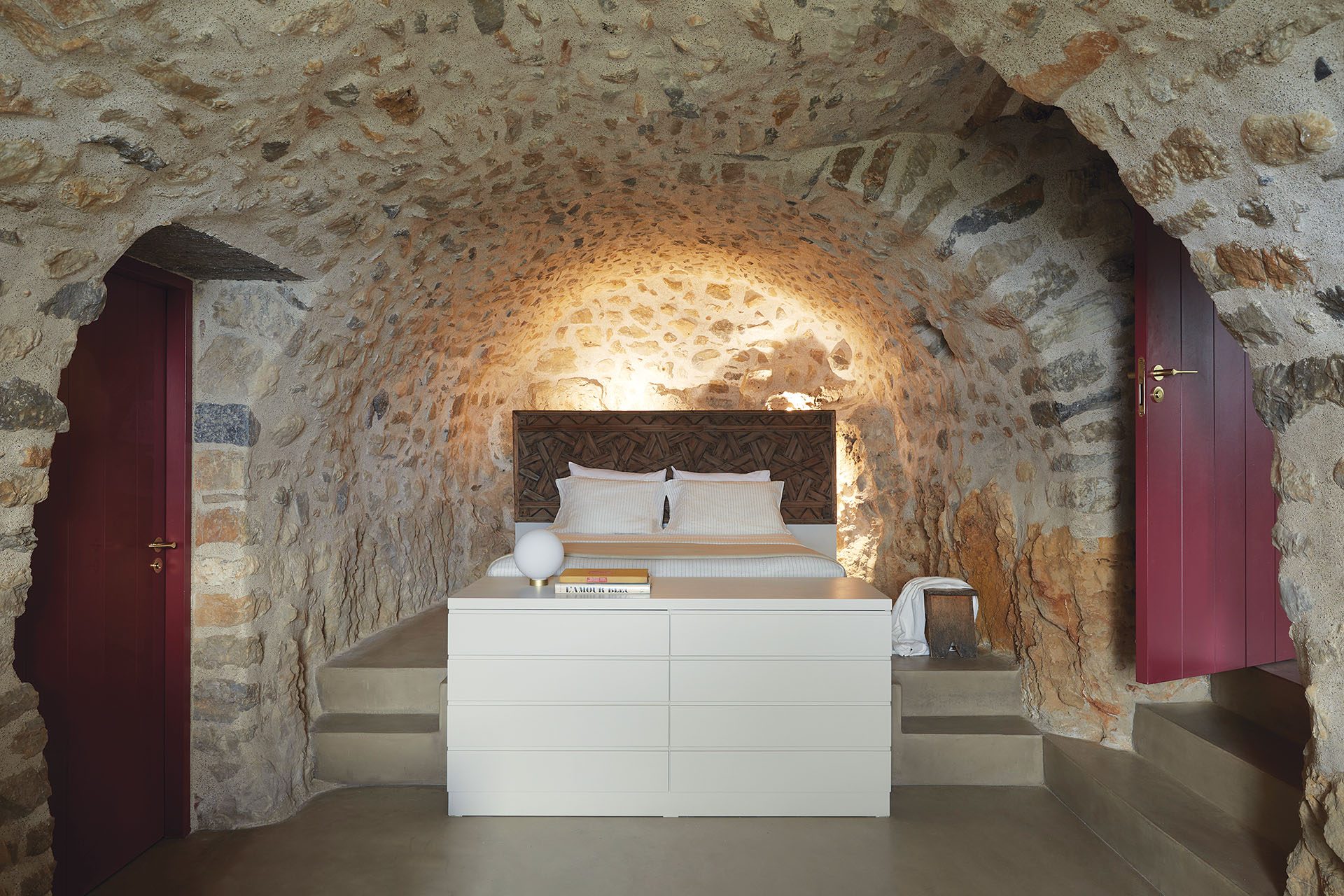 Vaulted stone bedroom with burgundy doors at Paratiritirio