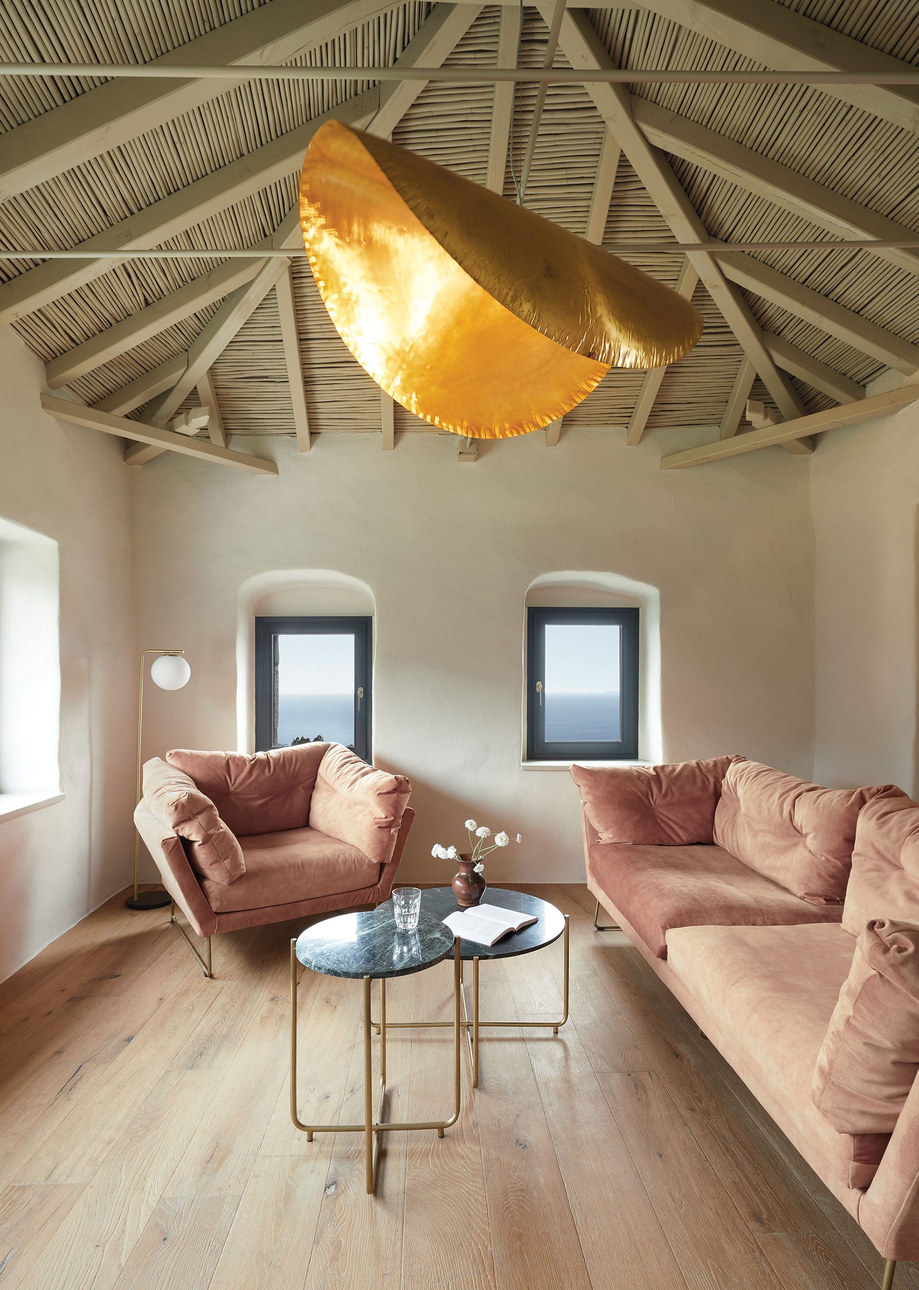 Living room with pink sofas and brass pendant at Paratiritirio