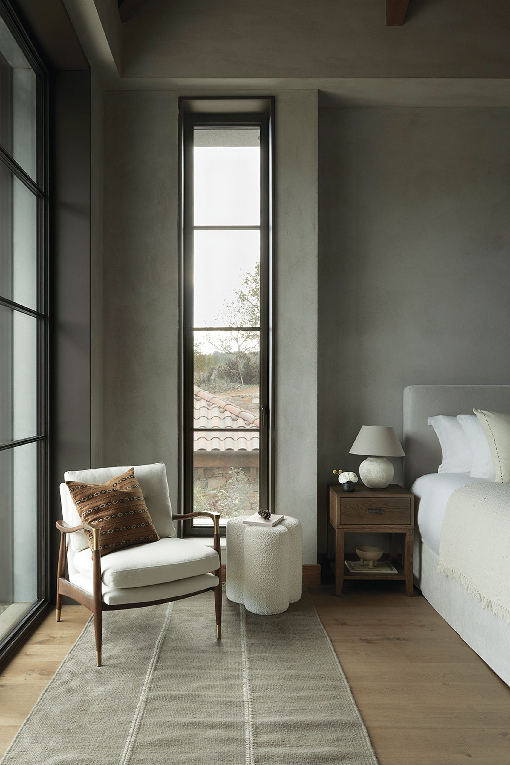 Bedroom with armchair and narrow tall window at Patrion House