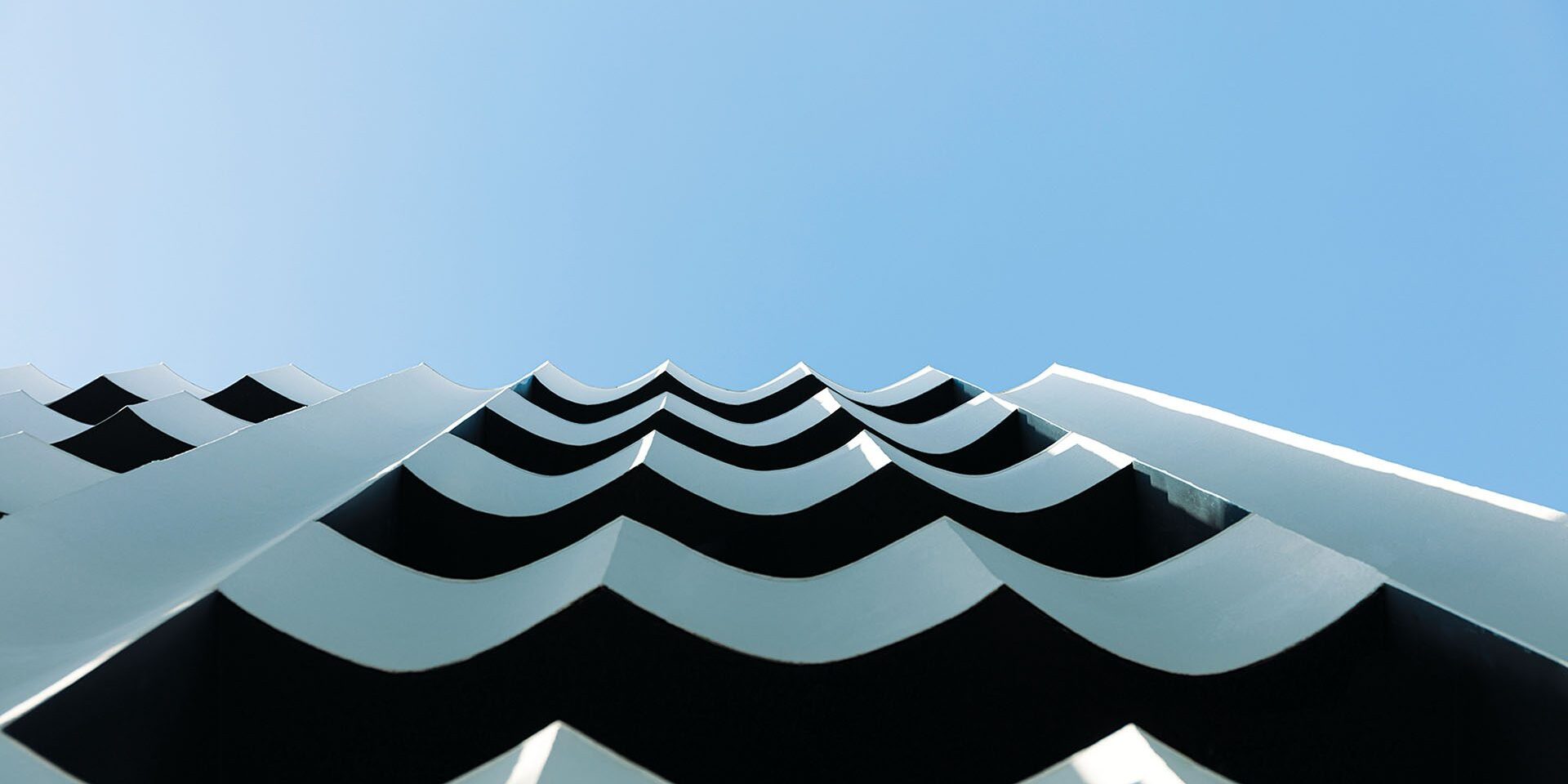 Undulating white façade of The Social Athens Hotel against the sky