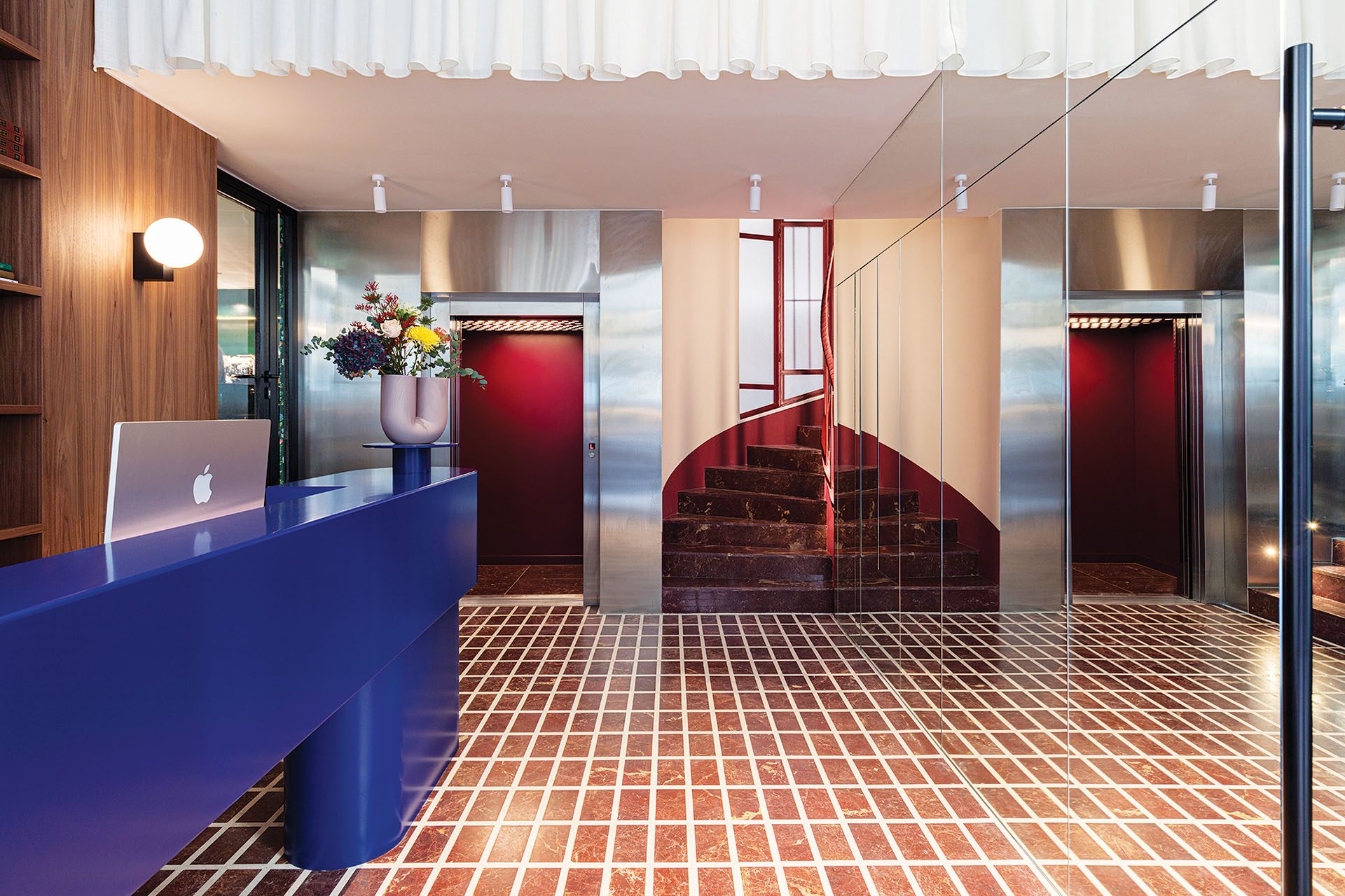 Cobalt-blue reception desk and mirrored surfaces at The Social Athens Hotel