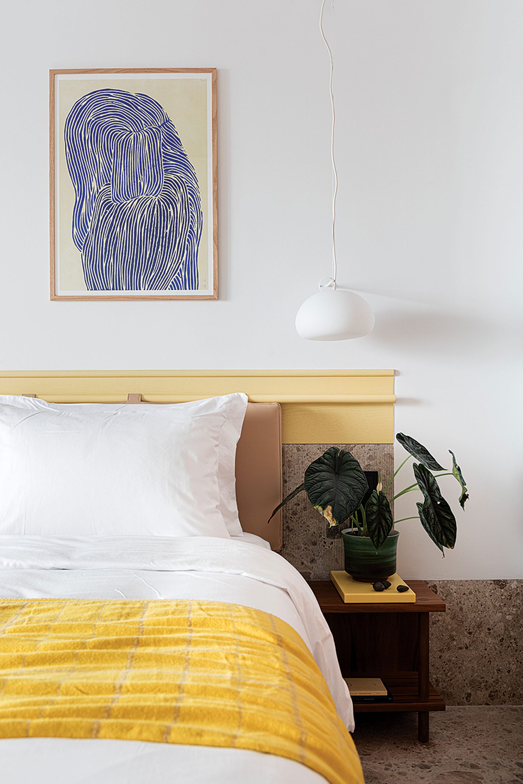 Guestroom bed with stone headboard and artwork at The Social Athens Hotel