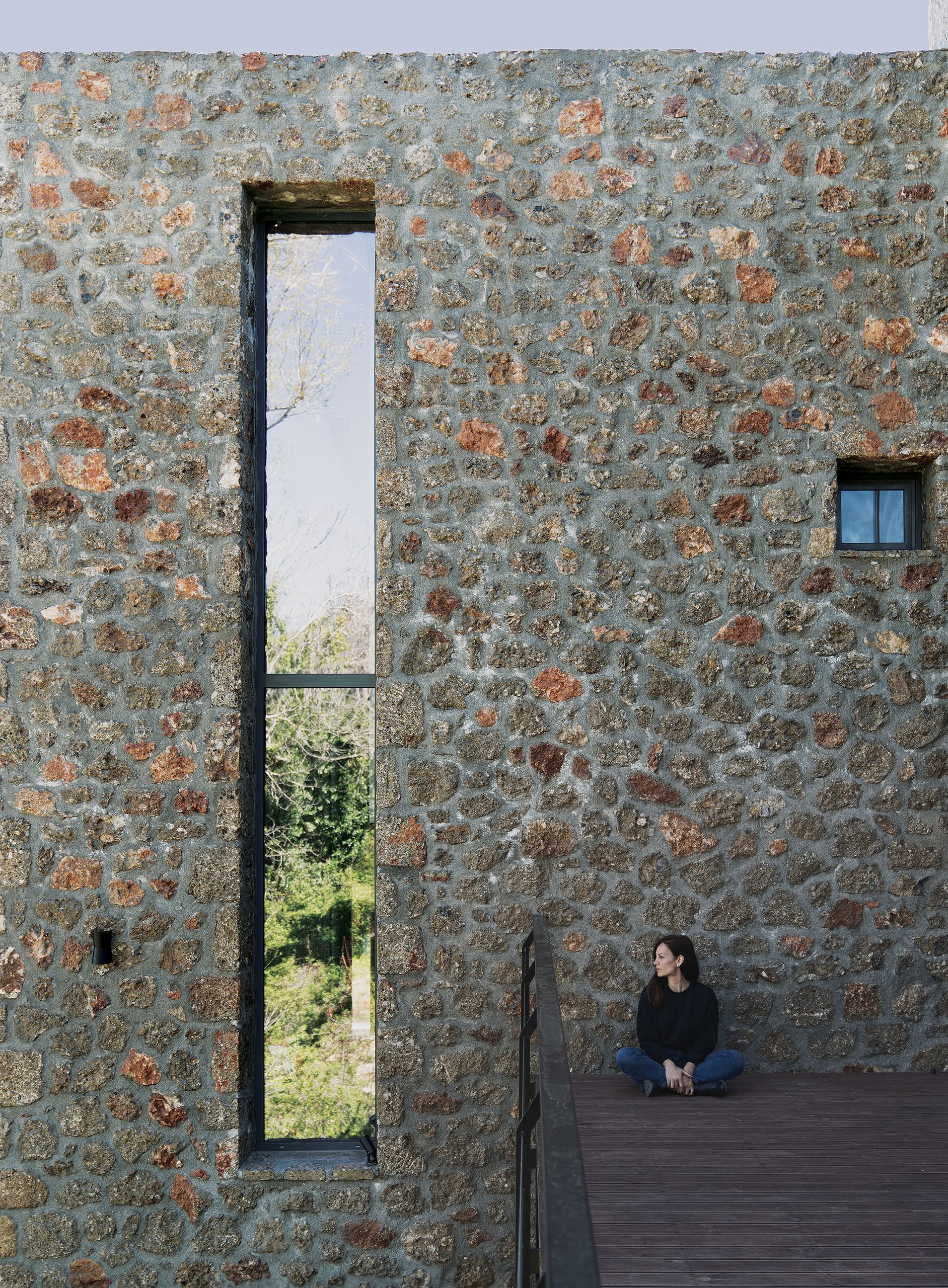 Stone wall with narrow vertical opening and timber deck at Slope