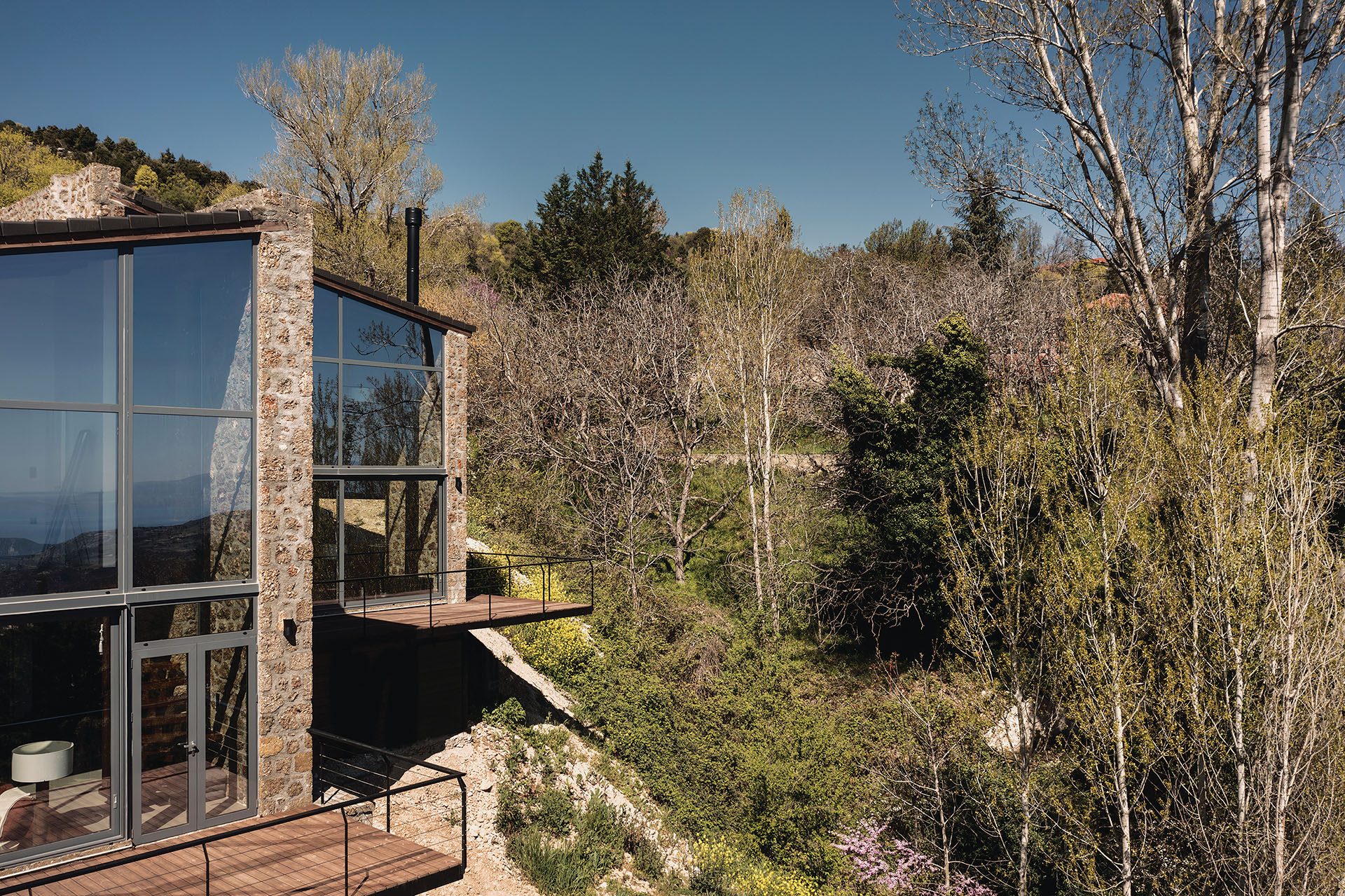 Glazed stone volume and timber deck of Slope among trees
