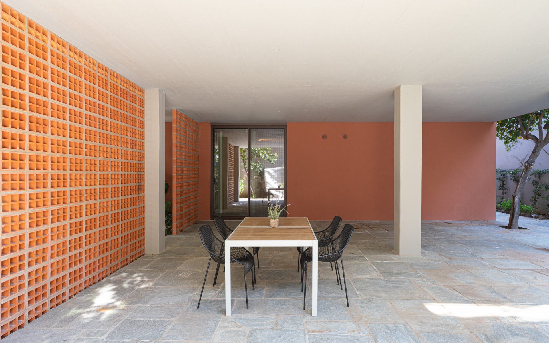 Pilotis of the Chalandri residence with ceramic claustra wall and dining table